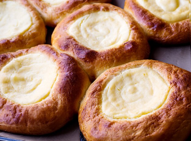 Open buns with cottage cheese (vatrushka) lying on a tray after baking. close up