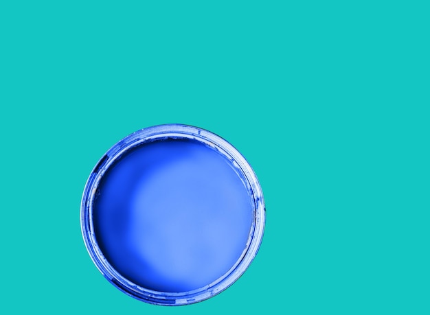 Open can with blue paint on green background top view