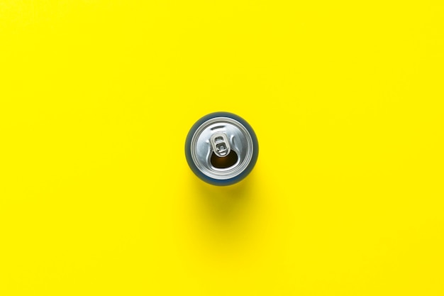 Photo open can with a drink or empty on a yellow background. minimalism. concept of day and night, caffeine, energy drink, holiday. flat lay, top view.