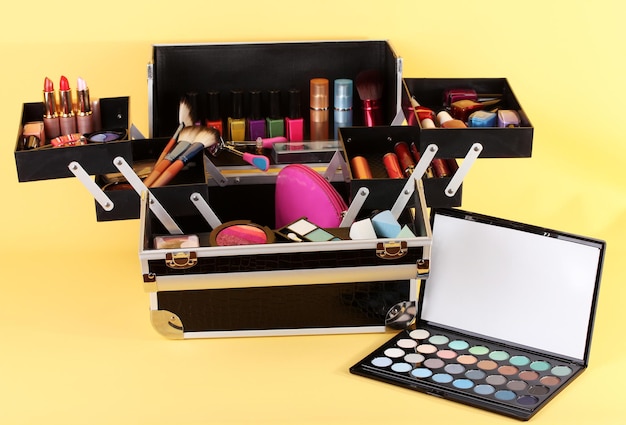 Open case with cosmetics on yellow background