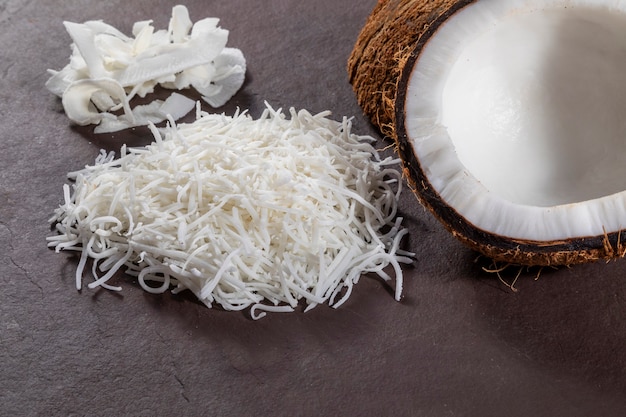 Open coconut in the middle on top of stone with coconut shavings and grated coconut.