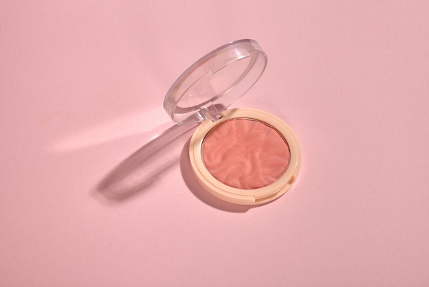 An open compact powder blush on pink background