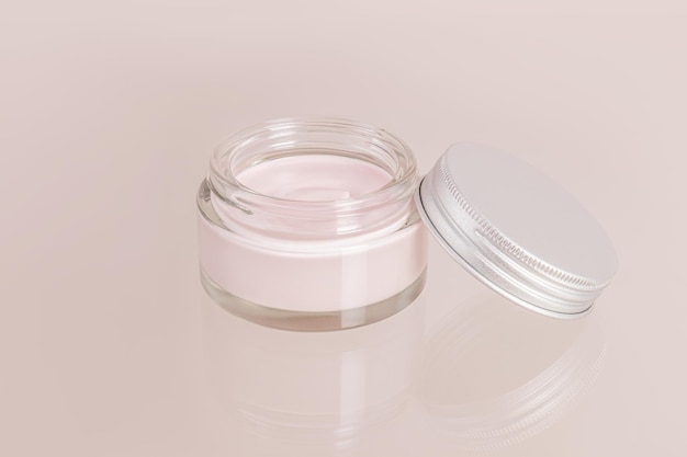 open cosmetic glass jar with cream for everyday selfcare on a beige background and a glass surface Front view a copy space