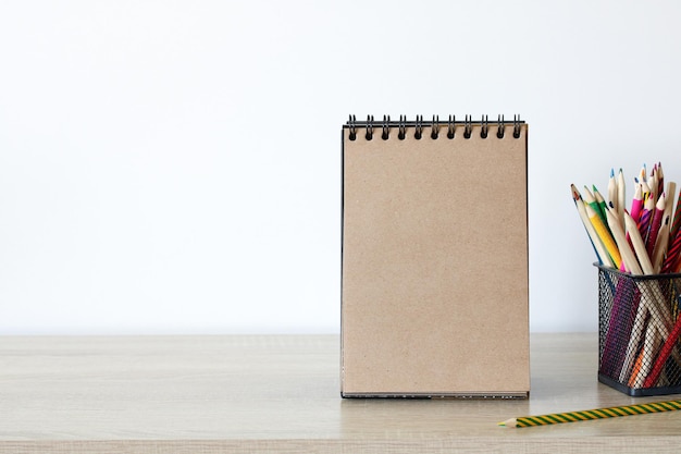 An open craft notebook with a blank page and colored pencils on the table