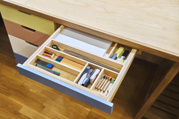 Open desk drawer with various school supplies arranged carefully in order before studies