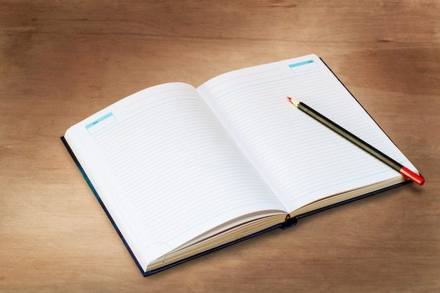 Open diary with a pencil lie on a wooden board, top view