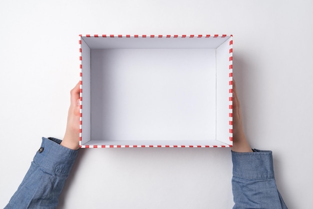 Open empty gift box in children's hands on white background Top view