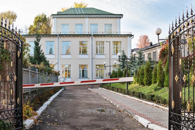 Open forged gates and a closed barrier at the entrance to the house