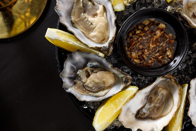 Open fresh oysters on a metal plate in ice on a concrete background