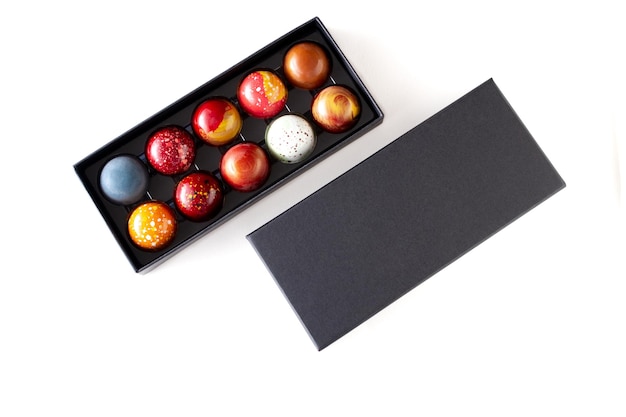 Open gift box with assortment of homemade chocolate bonbons Modern hand painted chocolate candy Product concept for chocolatier