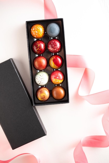 Open gift box with assortment of homemade chocolate bonbons Modern hand painted chocolate candy Product concept for chocolatier