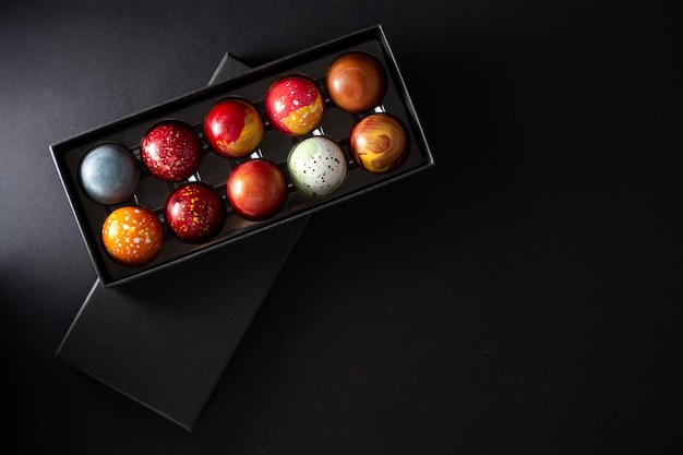 Open gift box with assortment of homemade chocolate bonbons Modern hand painted chocolate candy Product concept for chocolatier