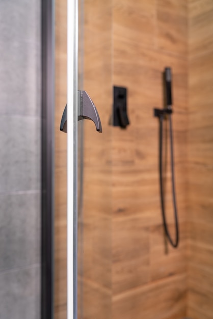 Open glass door to a modern wood effect shower cubicle in a home or apartment with close up focus to the handle