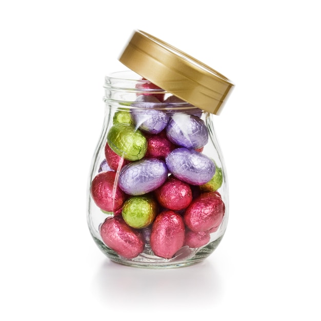 Open glass jar with chocolate candy Easter eggs wrapped in foil clipping path included