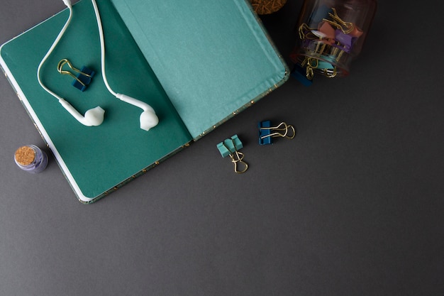 Open green page notebook with headphones and paper binder clips. Mockup minimalistic