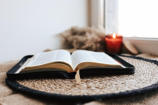 Open Holy Bible on a old wooden table and white wall background Religion concept Cozy warm photo