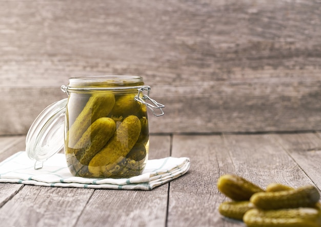 Open jar of marinated cucumbers on wooden table