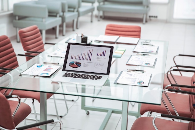 Open laptop computer with financial charts and papers spread out on the desktop before starting busi