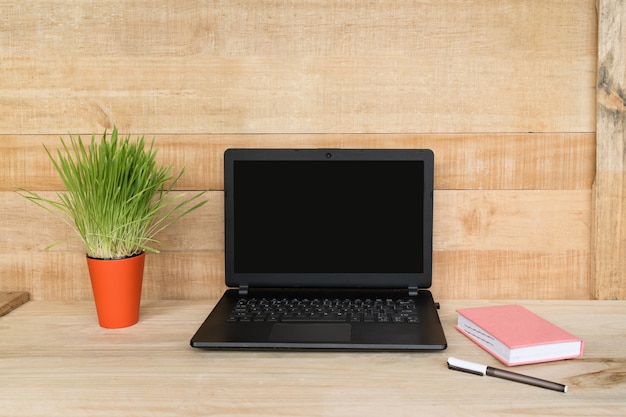 Open laptop, notebook and pen on wooden background