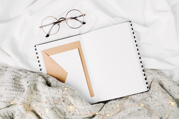 Open Mockup planner and glasses on bed with warm plaid. Copy space. Flat lay, top view