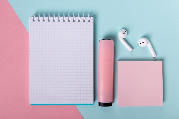 Open notebook marker pink stickers and headphones are beautifully laid out on a pink blue background...