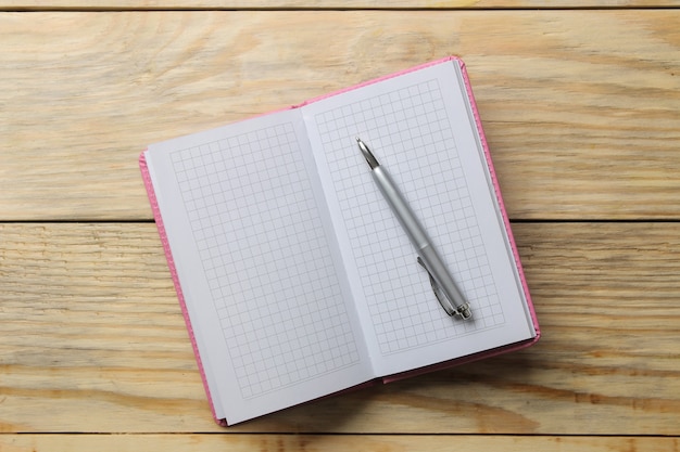 Open notebook and pen on the natural wooden table. top view. office tools