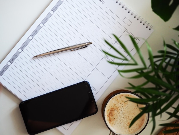 Open notebook with blank pages next to cup of coffee