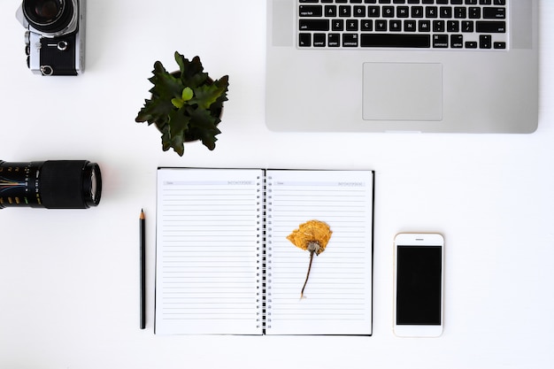 open notebook with flower blank pages, laptop, camera, lens 