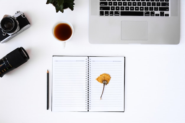 open notebook with flower blank pages, laptop, camera, lens 