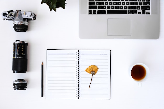 open notebook with flower blank pages, laptop, camera, lens 