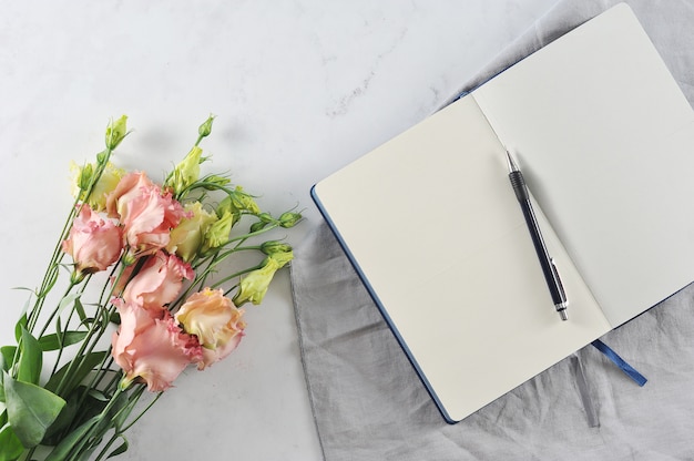 Open notebook with flowers on white marble