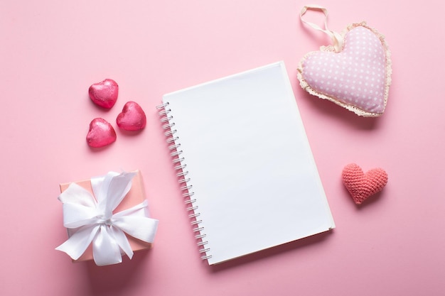 An open notebook with a gift and sweets on a light pink background Valentine's day