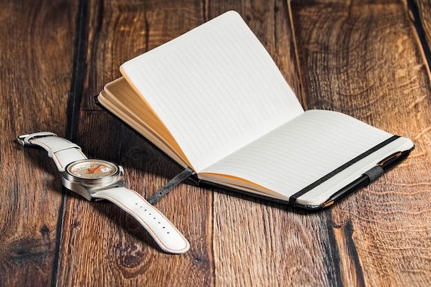 Open notebook with pen and wrist watch on table