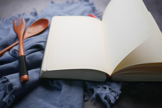 Open notepad and wooden spoon on table cloth