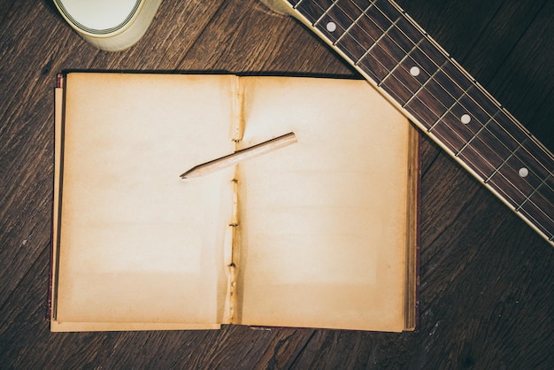 open old book and guitar on wooden table for your song or quote message