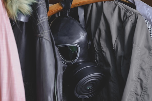 Open old closet in which a gas mask hangs between the clothes Coronavirus pandemic protect yourself