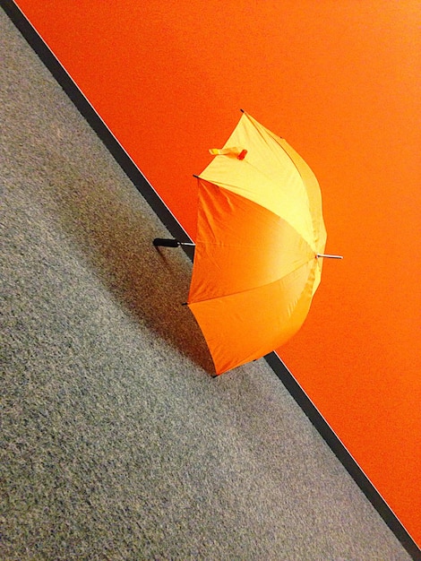 Open orange umbrella on floor