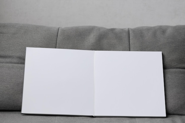 An open photo book with a white endpaper on a gray sofa background