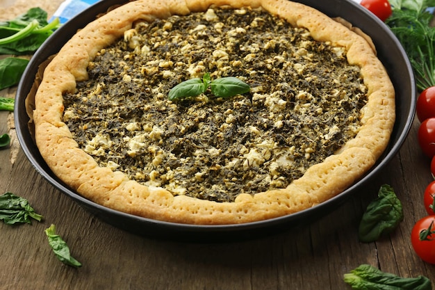 Open pie with spinach and tomato cherry on table close up