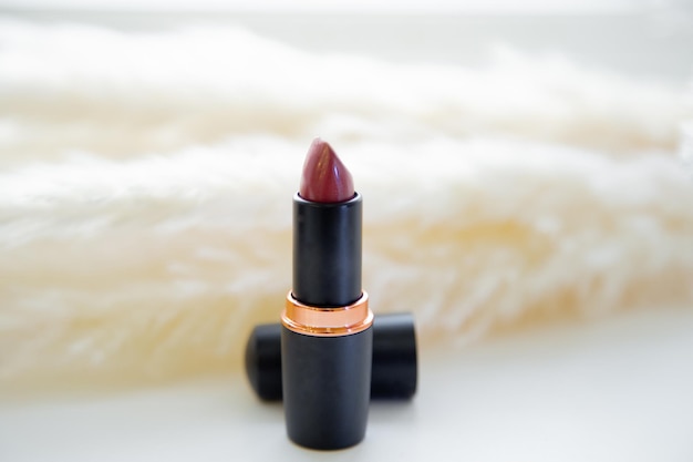 Open red lipstick stands on the background of fluffy reeds on a white background high quality photo