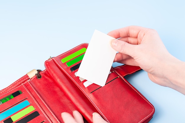 Open red purse and hands take a card Credit card in wallet Simple composition on blue background Hands take a card from a purse Pay money