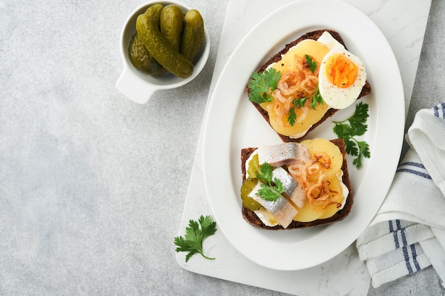 Open sandwich or smorrebrod with rye bread herring eggs caramelized onions parsley and cottage cheese on old wooden rustic table backgrounds Danish or Scandinavian traditional food snack lunch