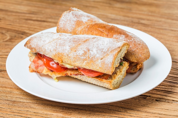 open sandwich with prosciutto, mozzarella and tomatoes on kitchen table, shallow focus