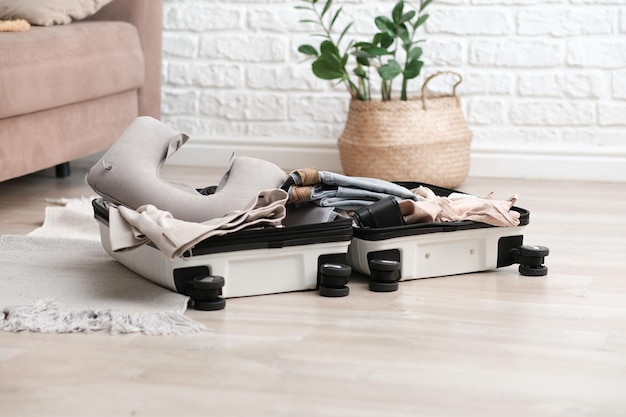 Photo open suitcase full of usual female clothes shoes and summer accessories on floor in living room