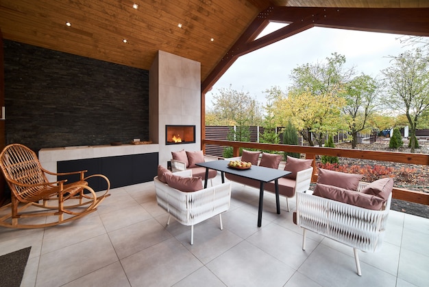 An open terrace with table, chairs, fireplace and apples.