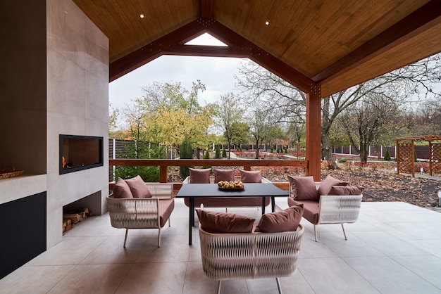 An open terrace with table, chairs, fireplace and apples.