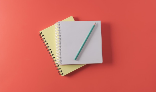 An open thick school notebook with a spiral spring and a pencil on top of an office notebook top view