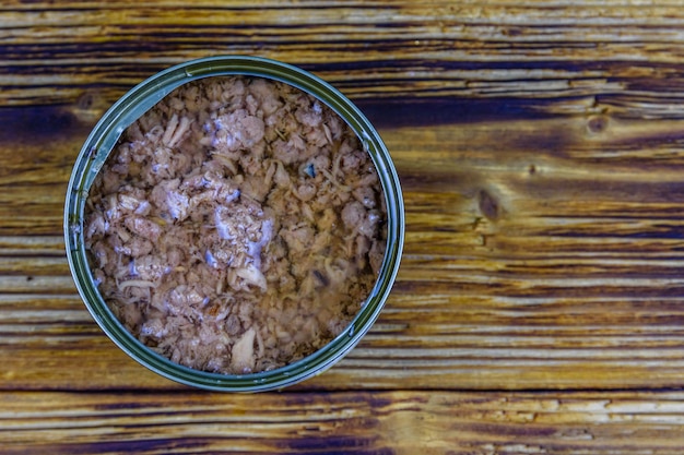 Open tin can with tuna fish on a wooden table