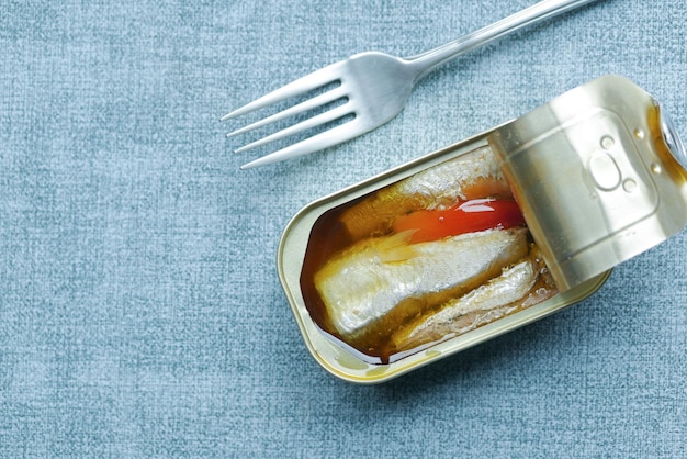 Open tin of sardines on white tiles background