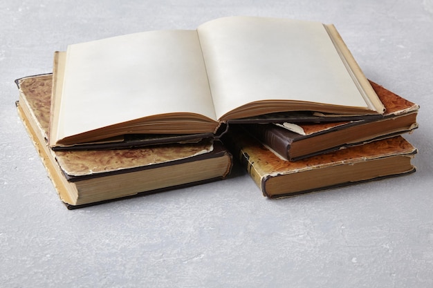 Open vintage book or notebook in a super jacket on a stack of old shabby books on a light concrete table